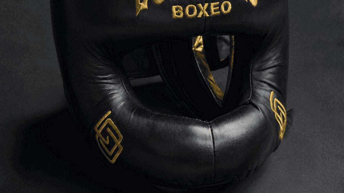 Detalle de la barra acolchada y la abertura frontal del casco negro y dorado ECHALEKU BOXEO