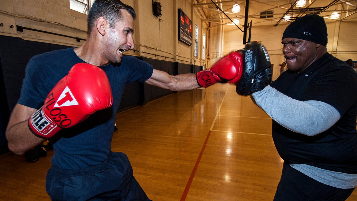 Boxeador de la All-Navy Boxing Team trabaja el golpe recto con manoplas durante una sesión de entrenamiento