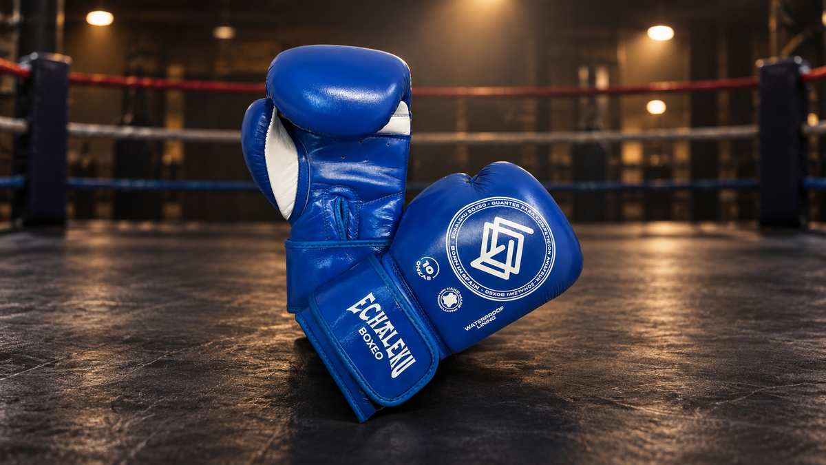 Guantes azules de competición amateur ECHALEKU BOXEO, con vistas de palma y dorso, en un montaje editorial ambientado en un ring.
