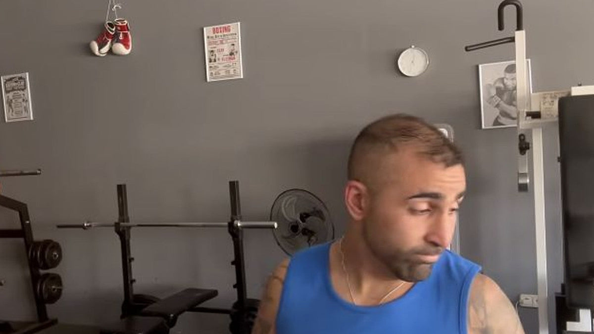 Entrenador en una zona del gimnasio con banco y barra de musculación.