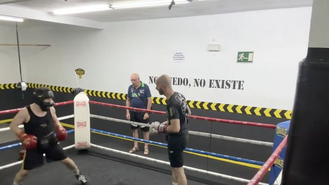 Dos boxeadores practicando en el ring bajo la observación de un entrenador.