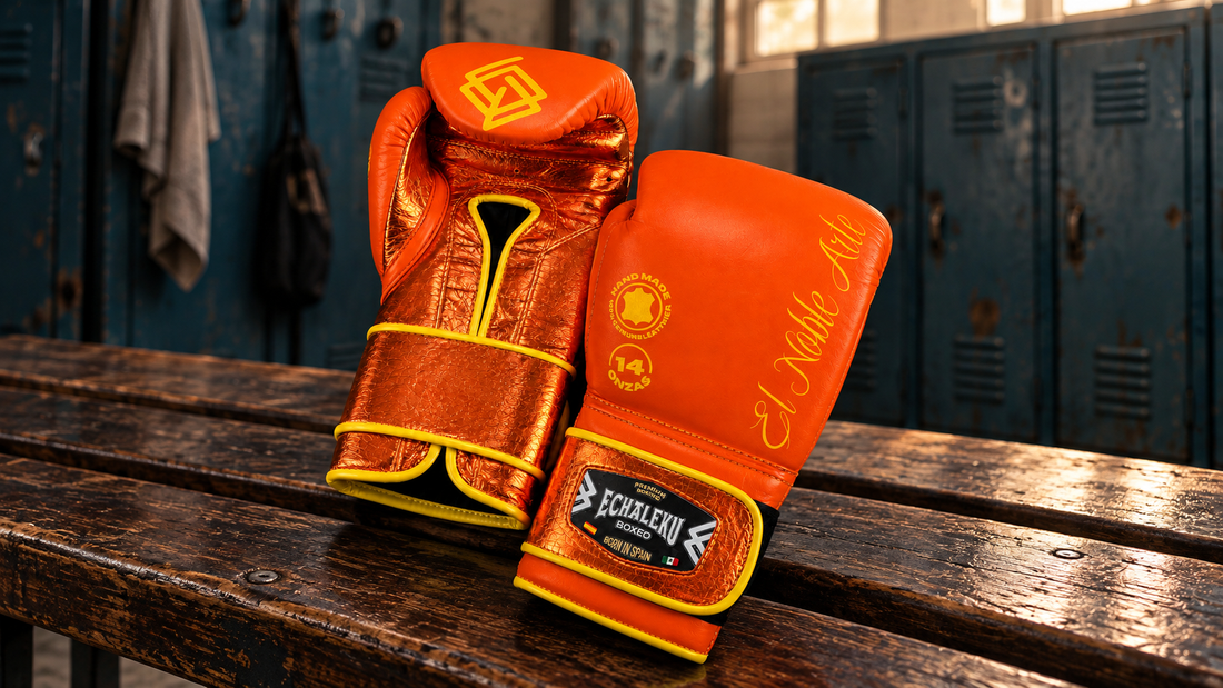 Guantes Guanajuato Teja Coral de ECHALEKU BOXEO apoyados en un banco de vestuario con taquillas.