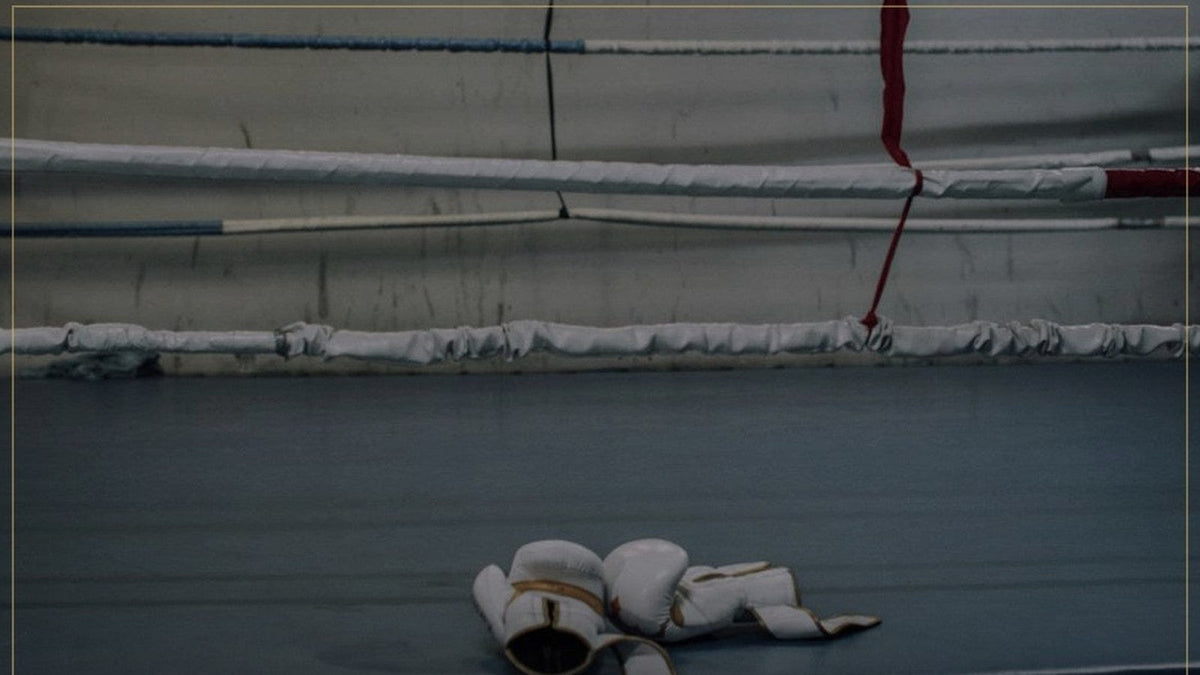 Guantes junto a las cuerdas de un ring de boxeo vacío